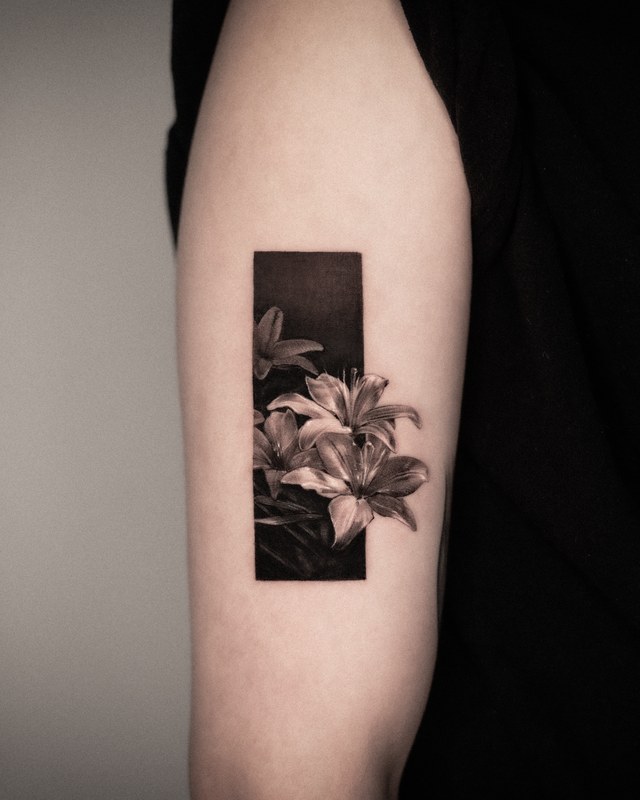 Lilies in a solid black frame tattooed on the arm