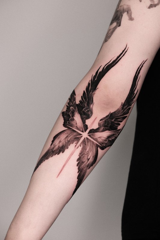 Angel wings and a star tattooed on the arm
