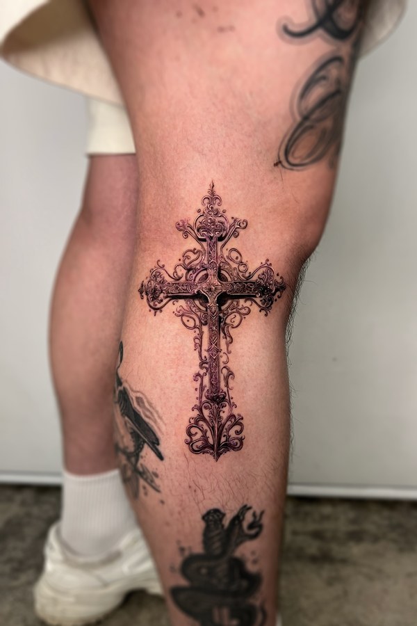 An ornamented cross tattooed on the calf