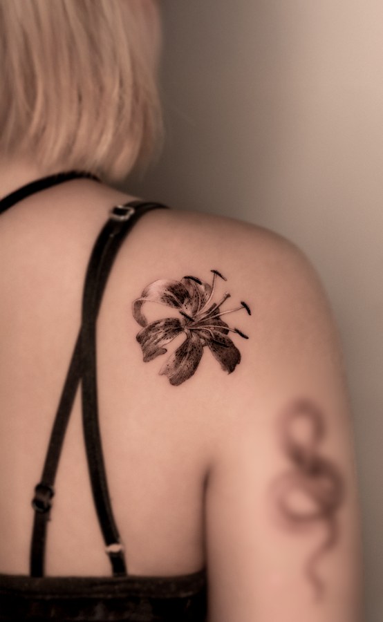 A lily tattooed on the shoulder