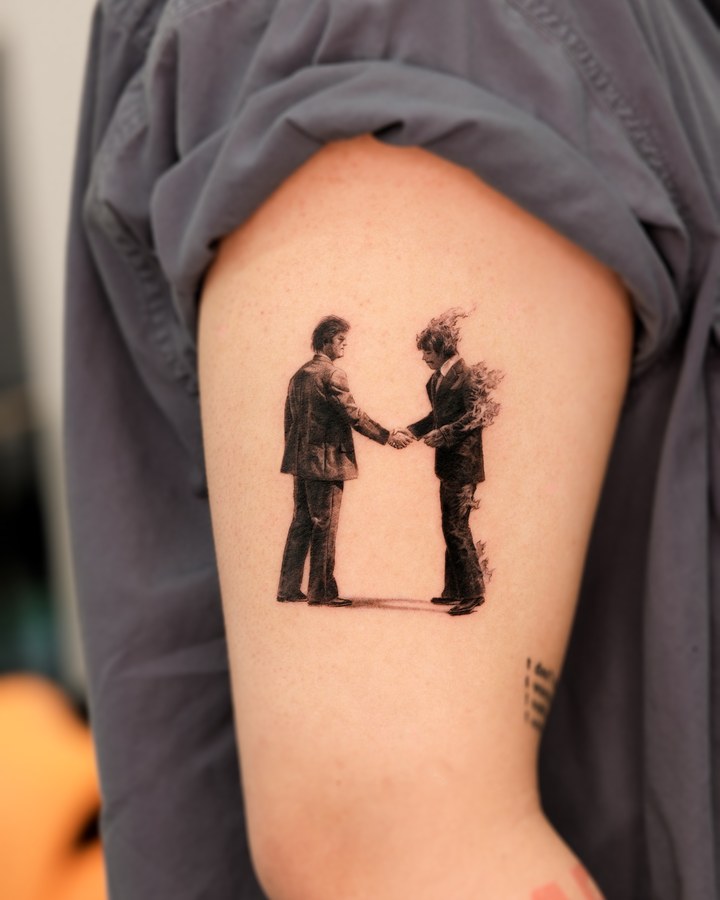 Two hands clasped, tattooed on the arm