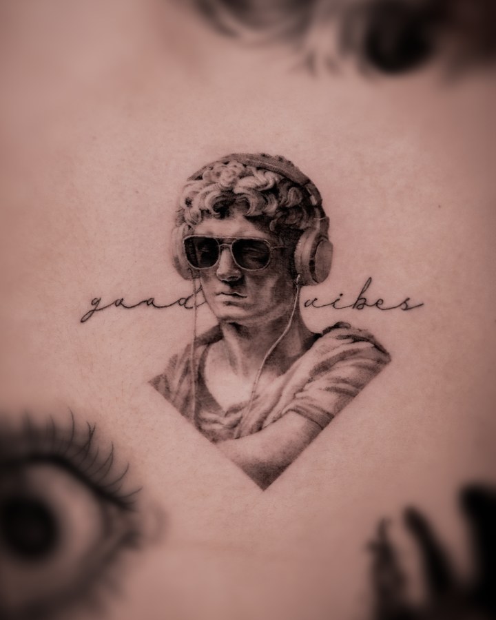 A plaster bust with script lettering, tattooed on the arm