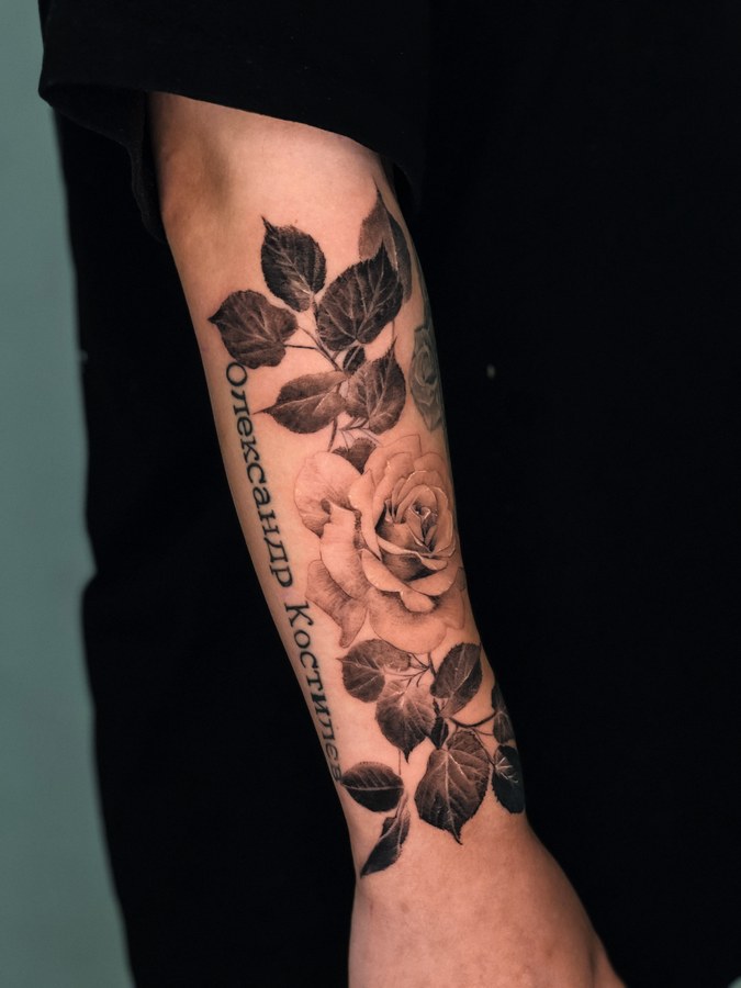 A rose vine with lettering, tattooed on the arm