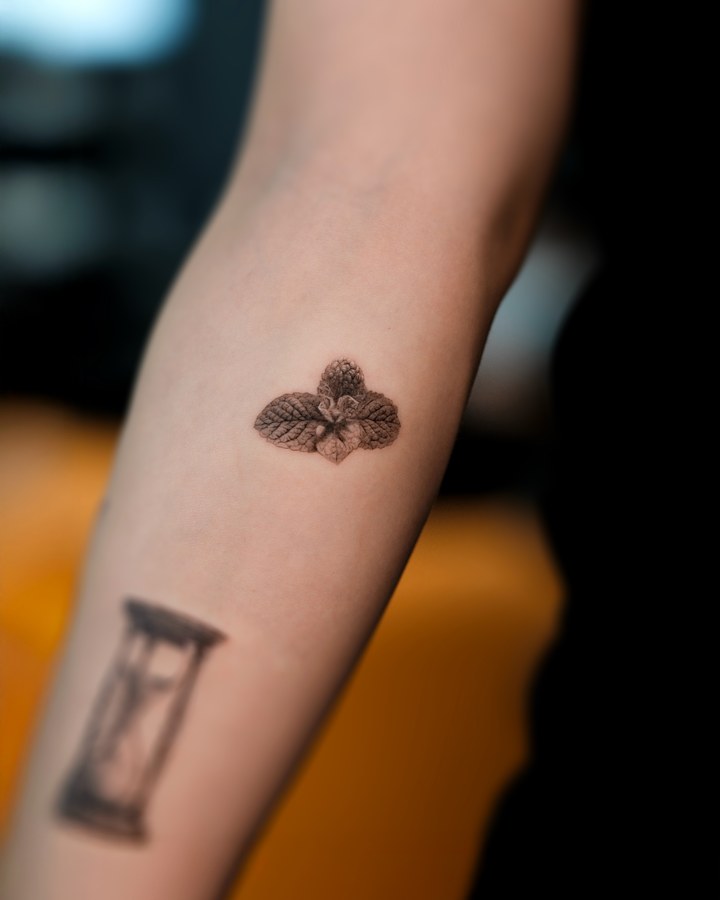 Small flowers and an hourglass tattooed on the arm