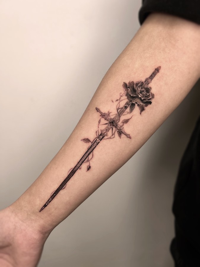 A sword and flowers tattooed on the arm