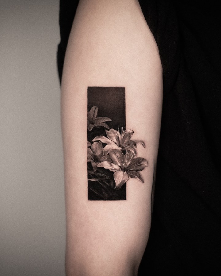 A lily in a black frame, tattooed on the arm
