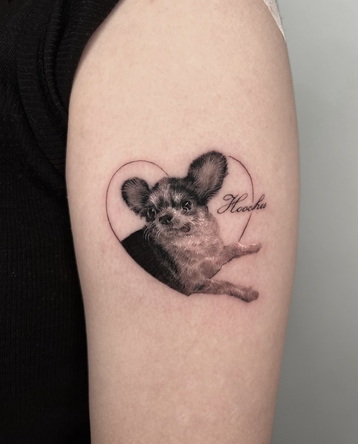 A portrait of a dog tattooed on the arm