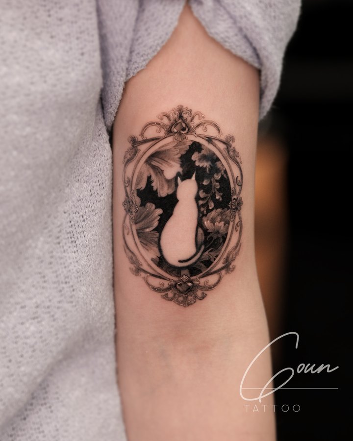 A cat inside a flower frame, tattooed on the arm