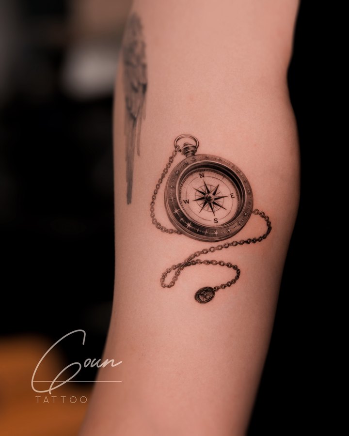 An antique compass tattooed on the arm