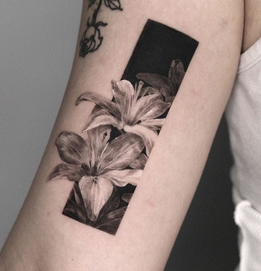 A lily with a black square frame, tattooed on the arm
