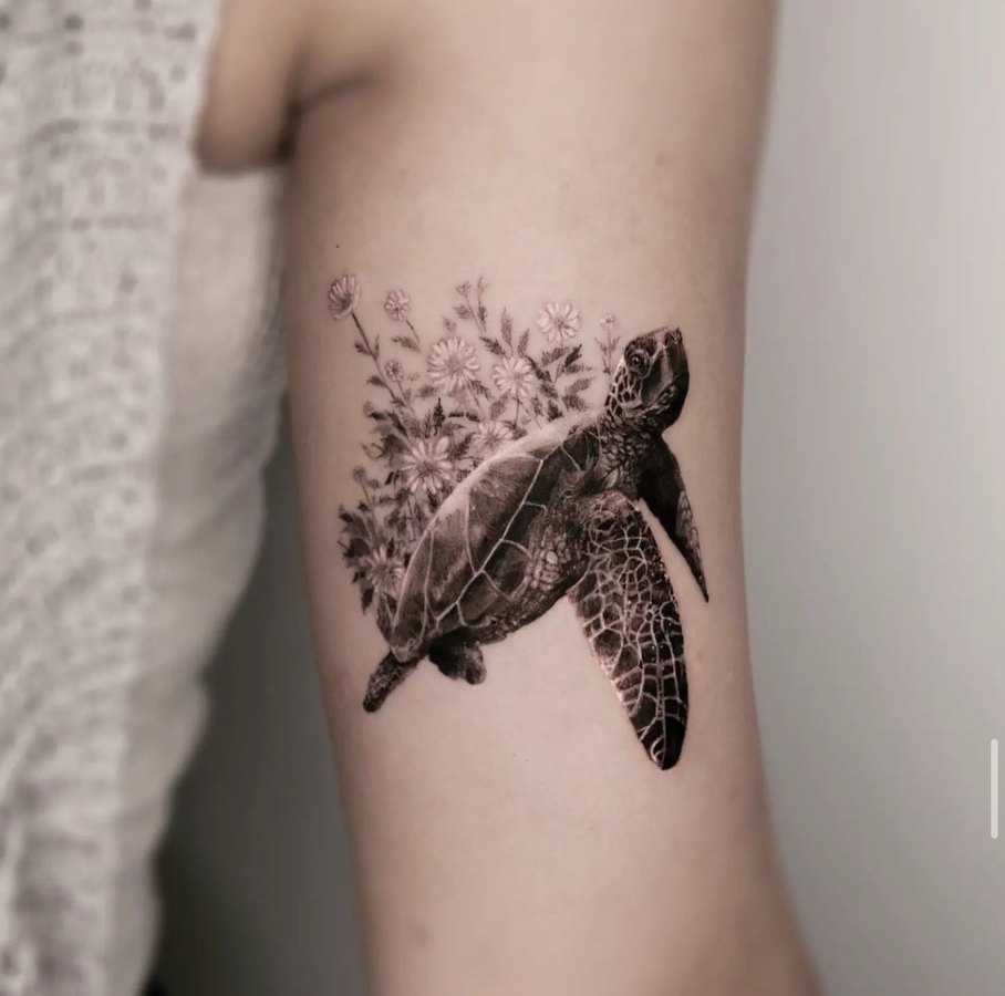 A sea turtle with flowers, tattooed on the arm